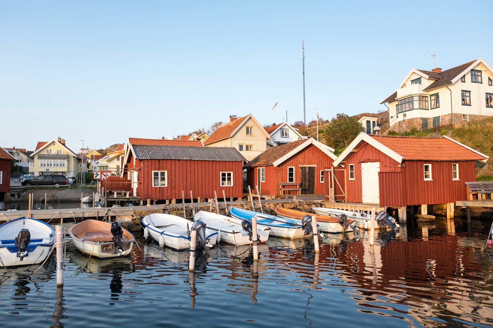Båtar vid bryggan framför röda sjöbodar